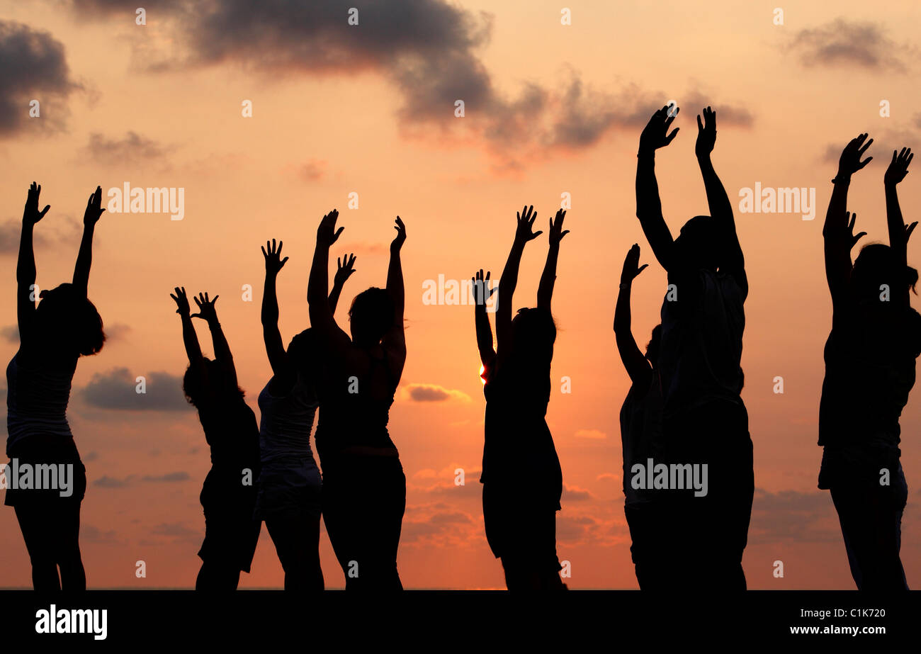 Un gruppo di persone che praticano lo yoga sulla spiaggia al tramonto, Jaco, Costa Rica Foto Stock