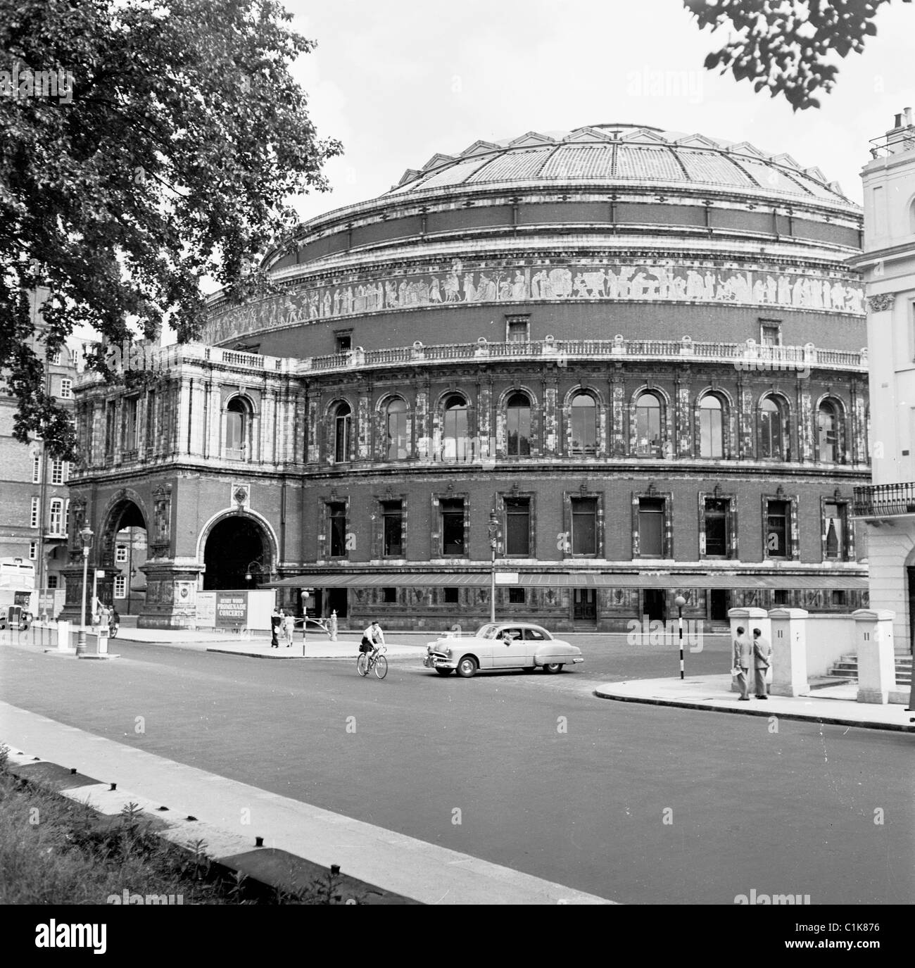 Londra, 1950s. Una fotografia da J Allan contanti. Una macchina si ferma per un ciclista su strada al di fuori della Royal Albert Hall. Foto Stock