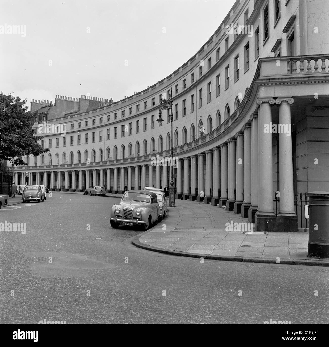 Anni '1950, auto storiche dell'epoca parcheggiate in una mezzaluna di grandi case Regency vicino a Regents Park, Londra, Inghilterra. Foto Stock