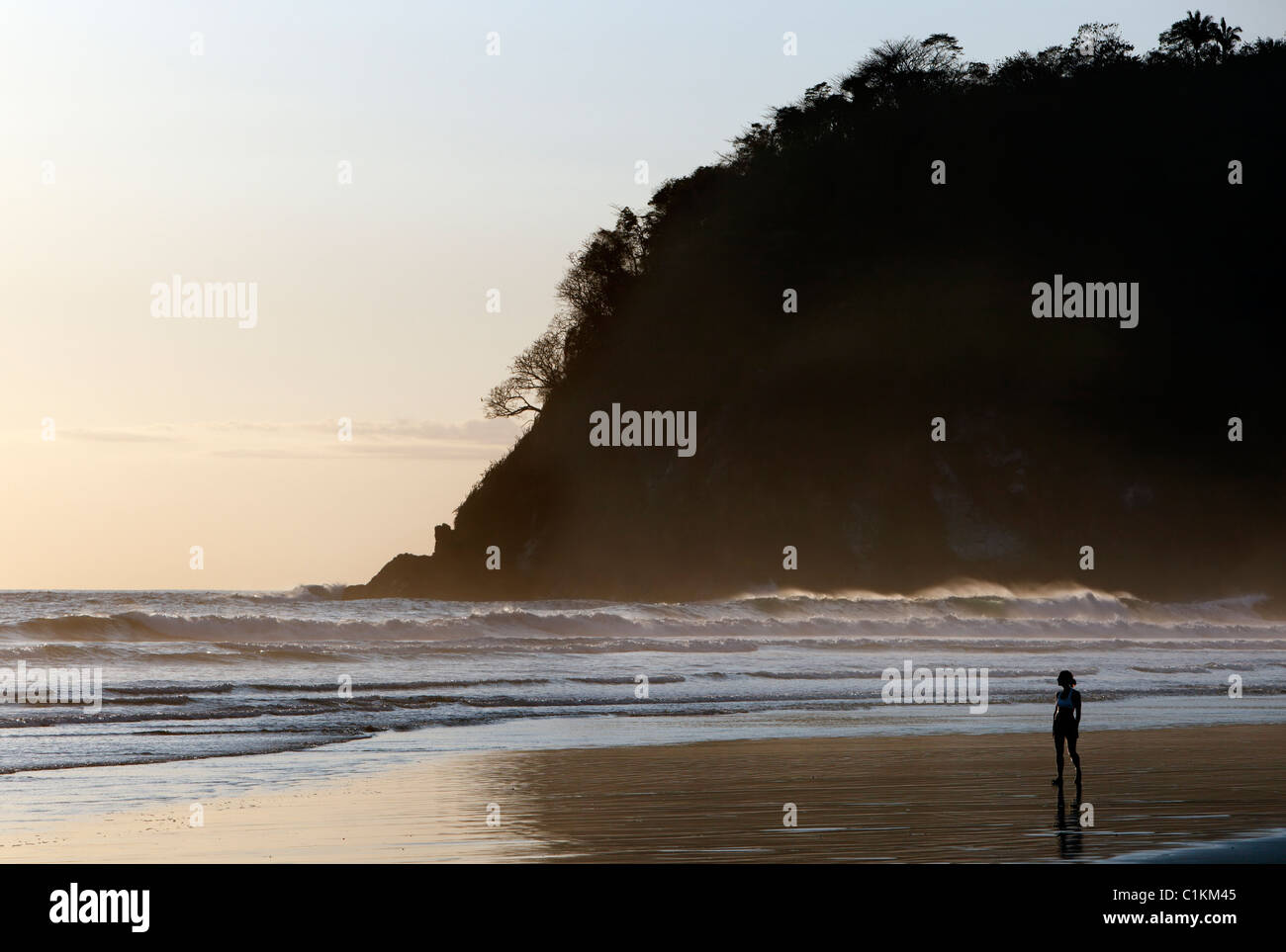Una donna di camminare sulla spiaggia al tramonto, Playa San Miguel, Nicoya peninsula, Costa Rica Foto Stock