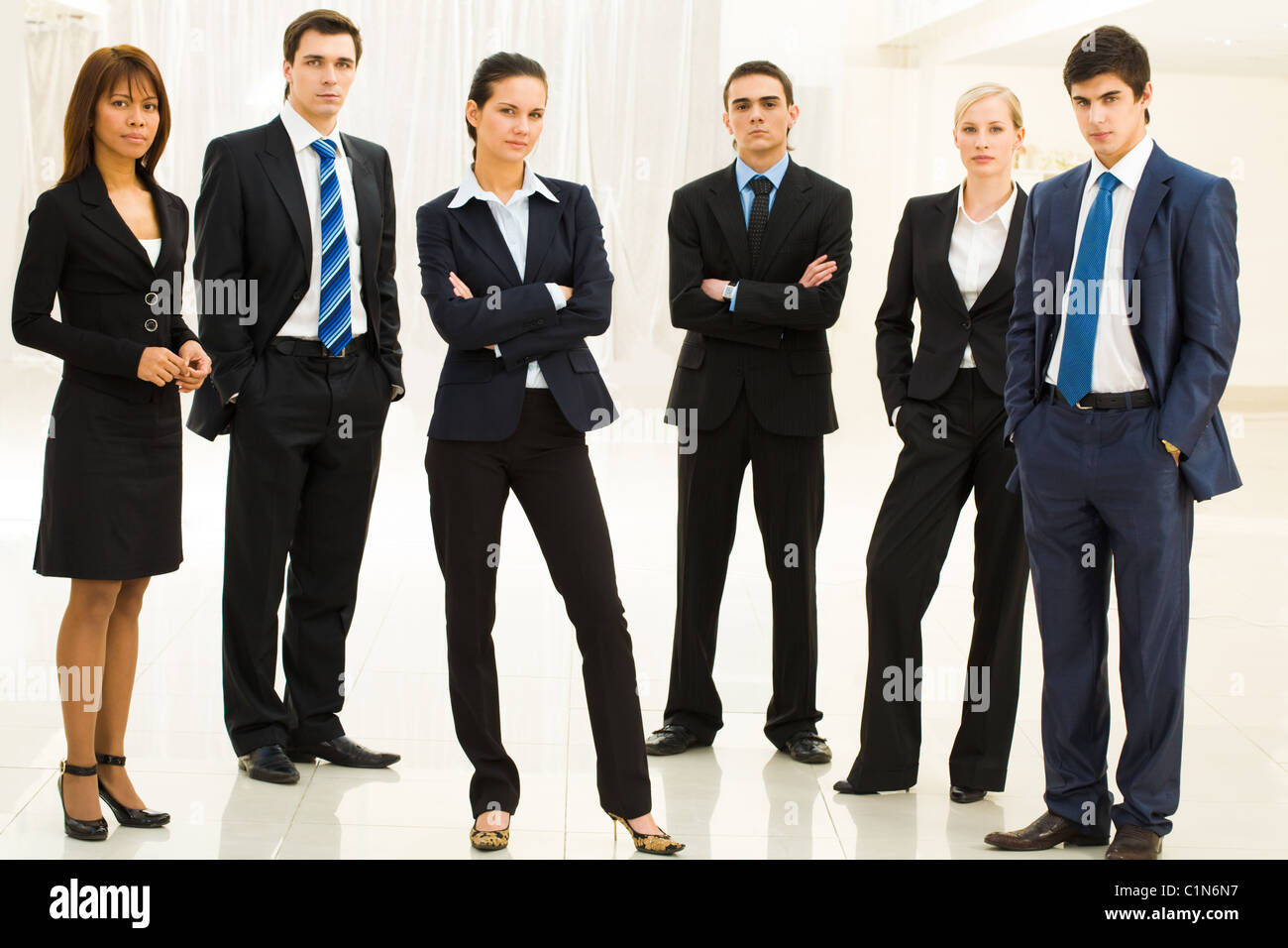 Ritratto di fiducia ben vestito la gente di affari in piedi in semicerchio con smart lady in centro Foto Stock