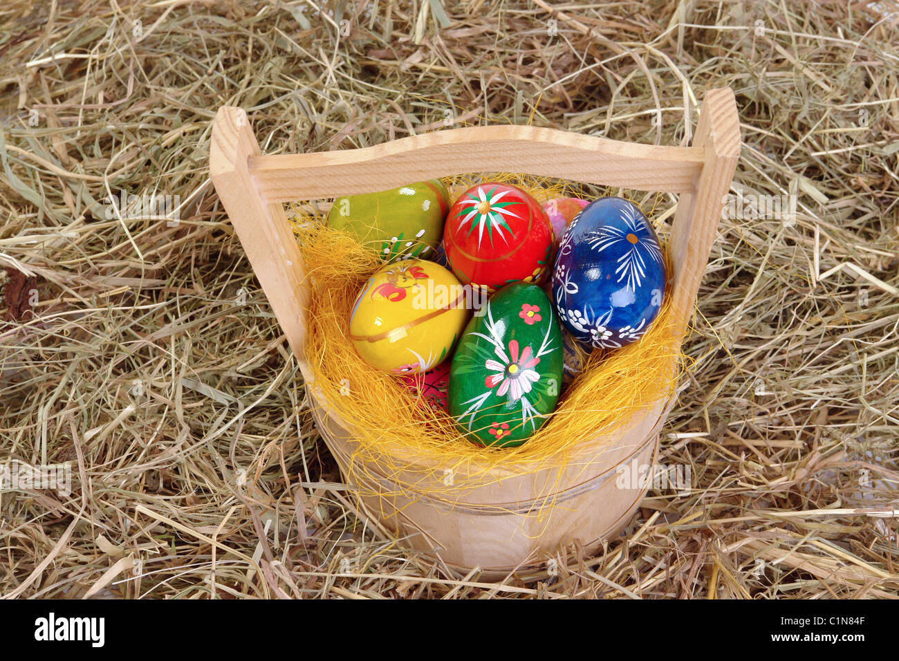 Dipinto di uova di pasqua nel cesto di legno su sfondo di fieno Foto Stock