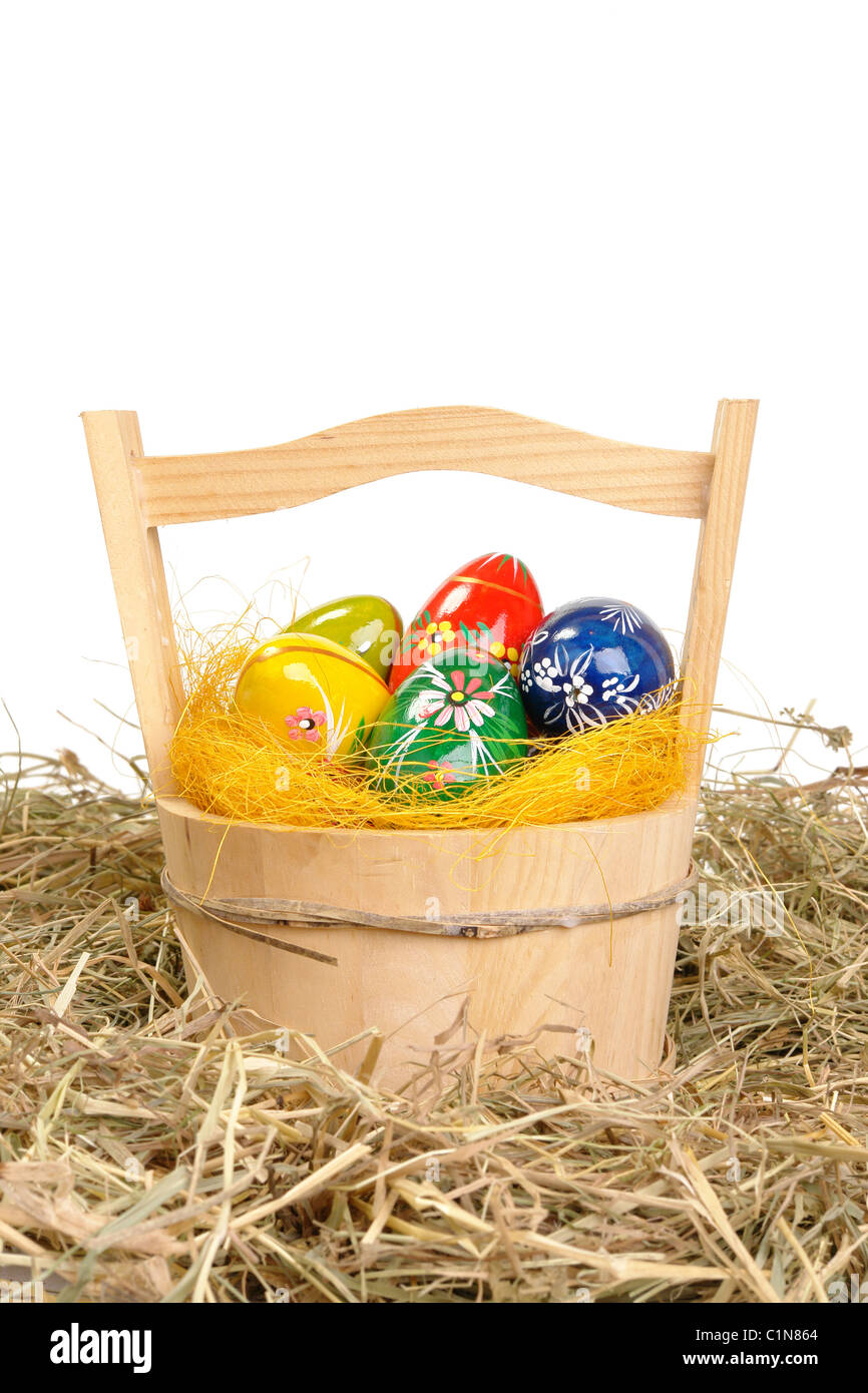Dipinto di uova di pasqua nel cesto di legno sul fieno su sfondo bianco Foto Stock