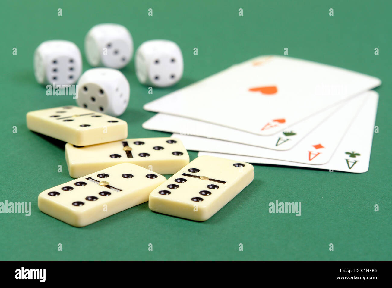 Quattro pezzi di domino, aces e muore sul tavolo verde panno Foto Stock