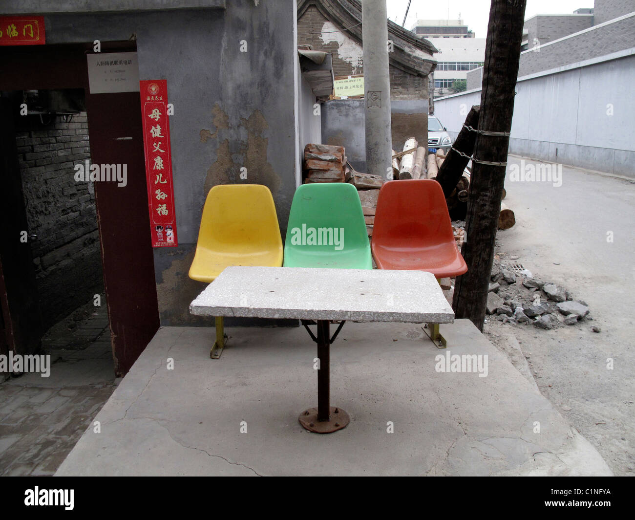 La Cina al di fuori del tavolo sedie multi-colore verde giallo rosso segni porta porta di legno cemento grigio grigio Foto Stock