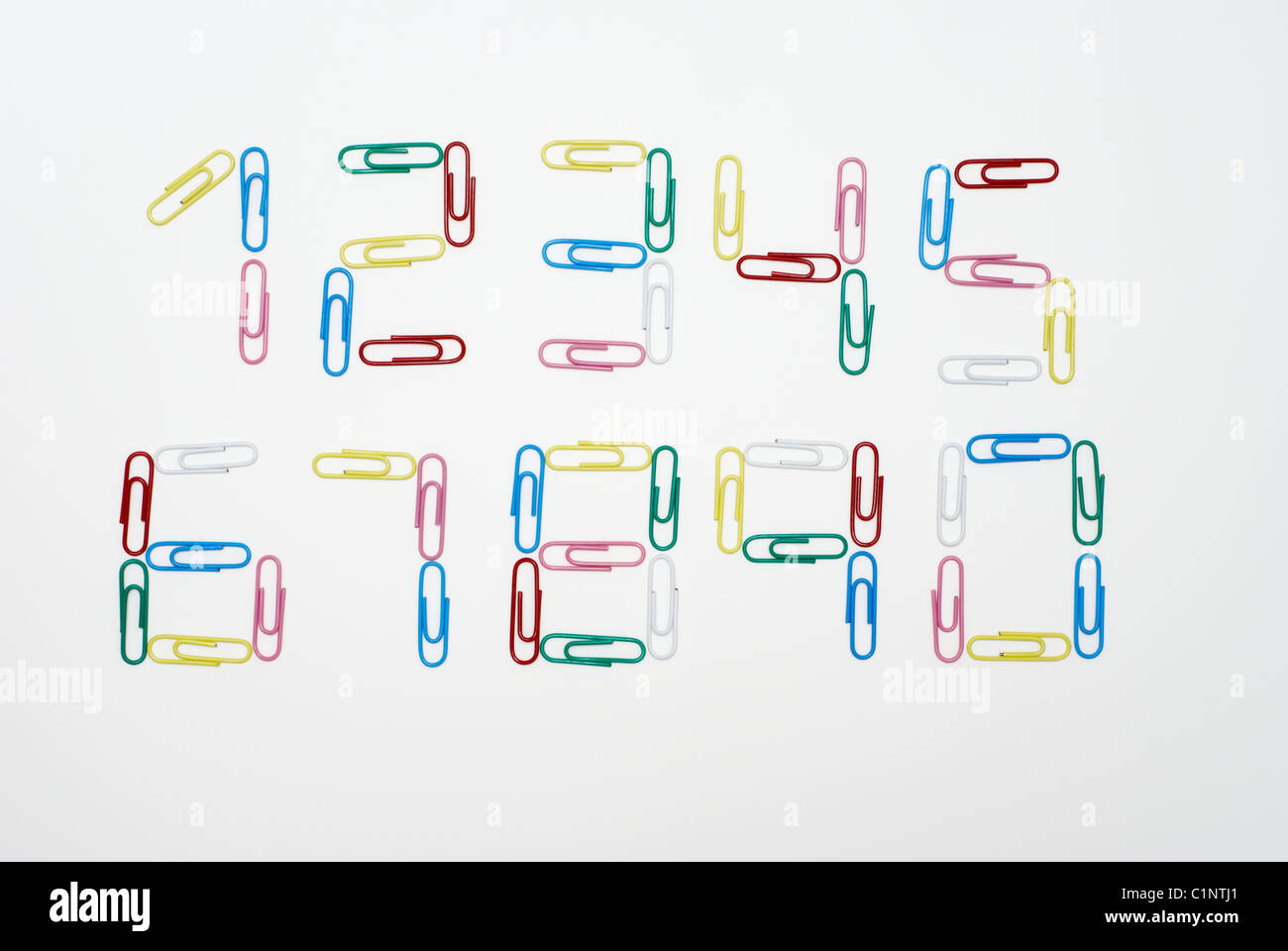 Numeri da zero a nove realizzato con multicolore fermagli per carta fotografato su sfondo bianco Foto Stock