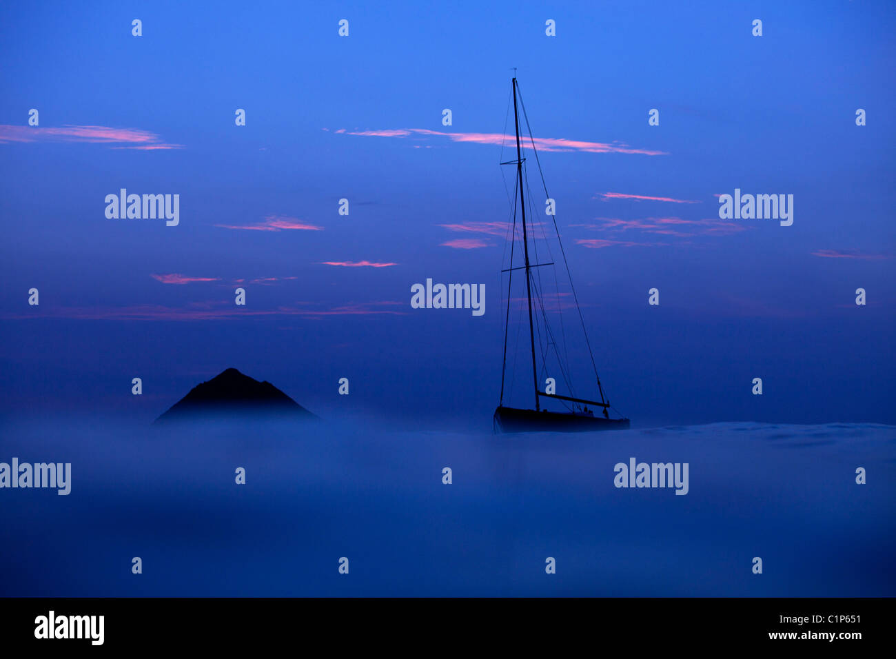 Un mistico mattina a Lanikai beach come una barca a vela si appoggia nella Baia di Kailua vicino al Mokulua Isole Hawaii. Foto Stock