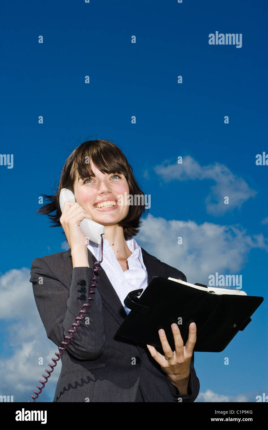 Ritratto di imprenditrice al telefono contro il cielo blu Foto Stock
