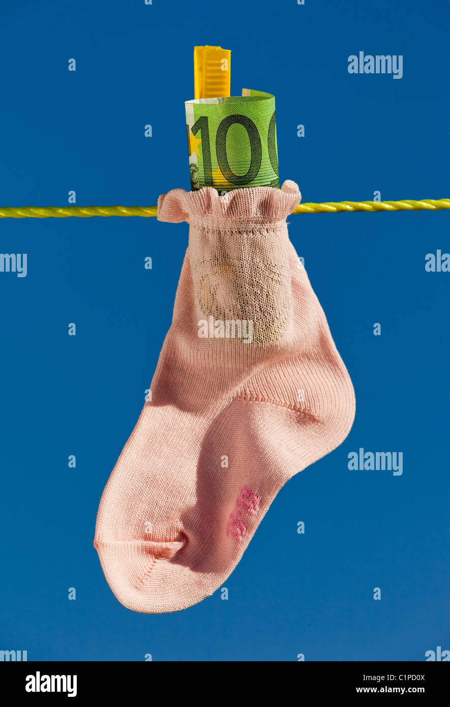 Baby calze su stendibiancheria con le banconote in euro Foto Stock