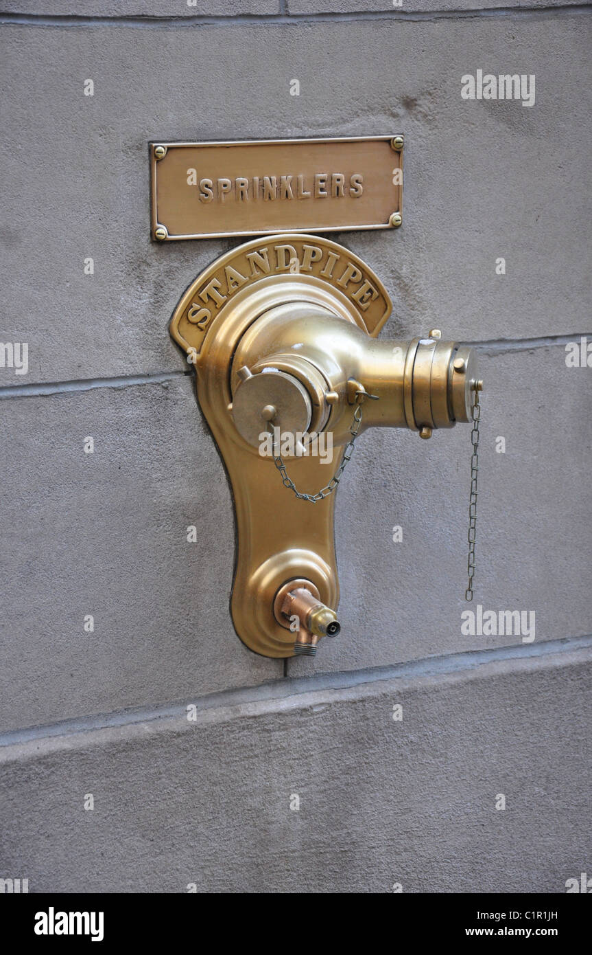 Un ottone idrante montato su una parete con tubo montante sprinkler e etichettato Foto Stock Un ottone idrante montato su una parete con tubo montante sprinkler e etichettato Foto Stock