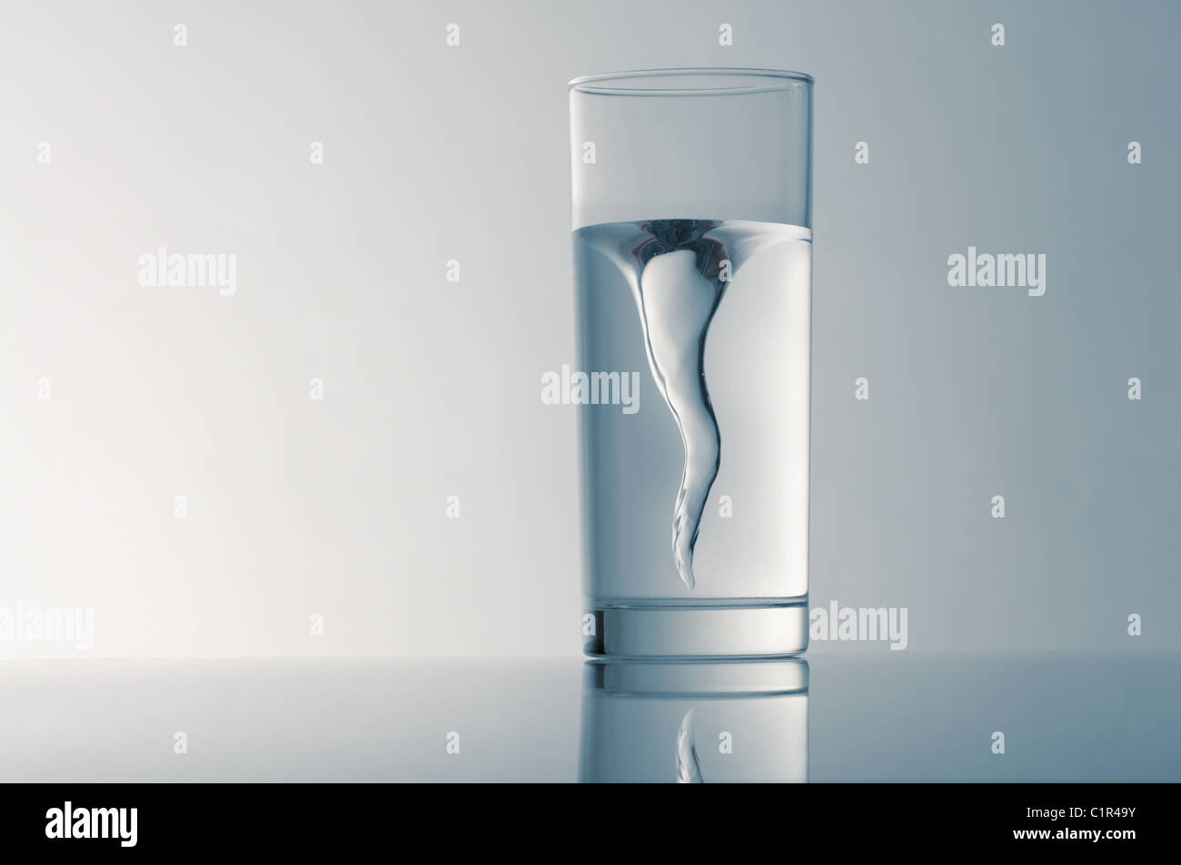 Vetro con acqua sorgiva contro uno sfondo blu Foto Stock