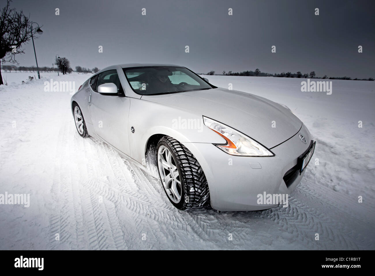 Auto sportiva bloccata in un campo innevato con piste per pneumatici a terra. Foto Stock