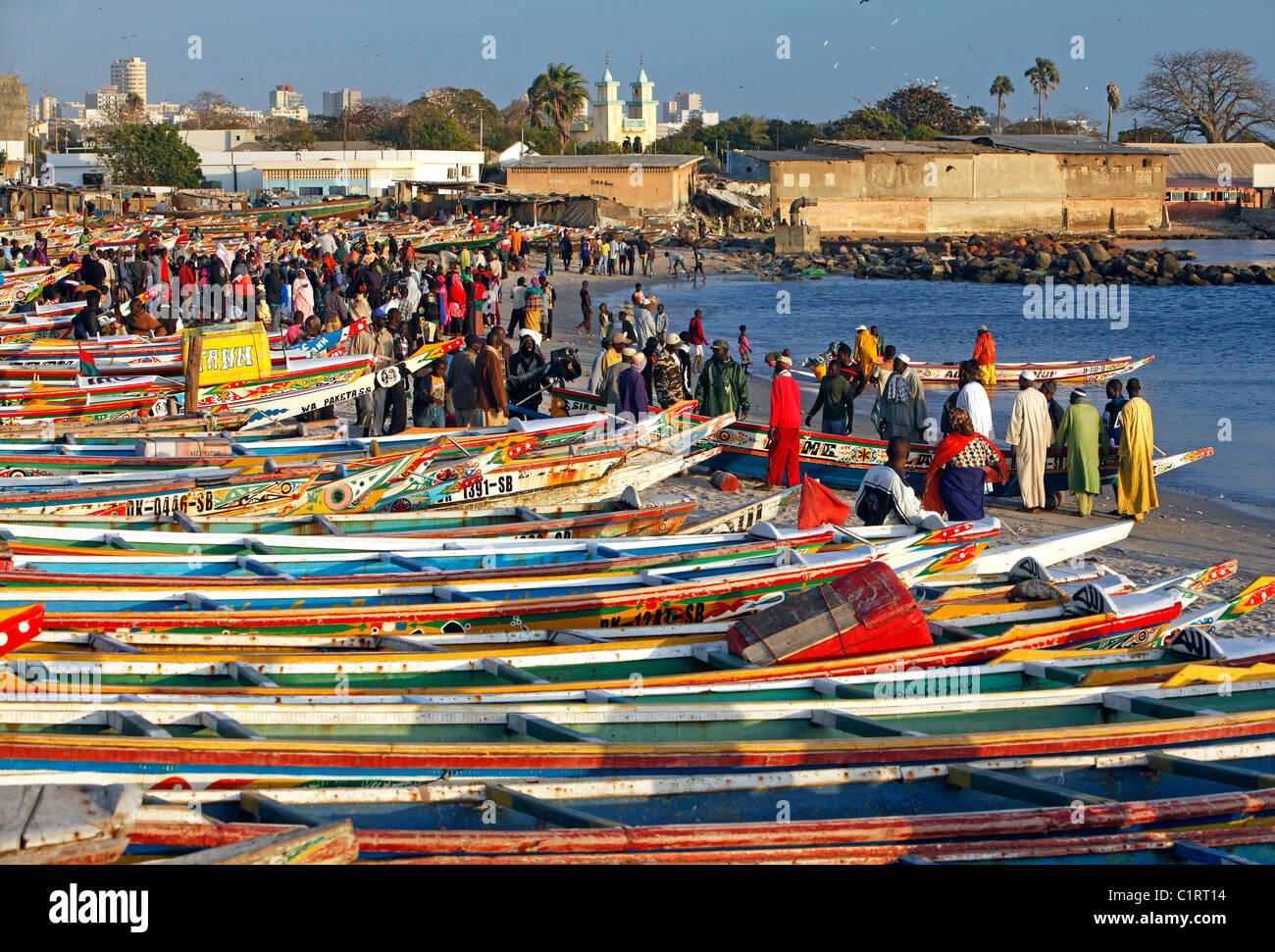Colorfully dipinto barche da pesca la linea della spiaggia presso il mercato del pesce di Dakar in Senegal Foto Stock