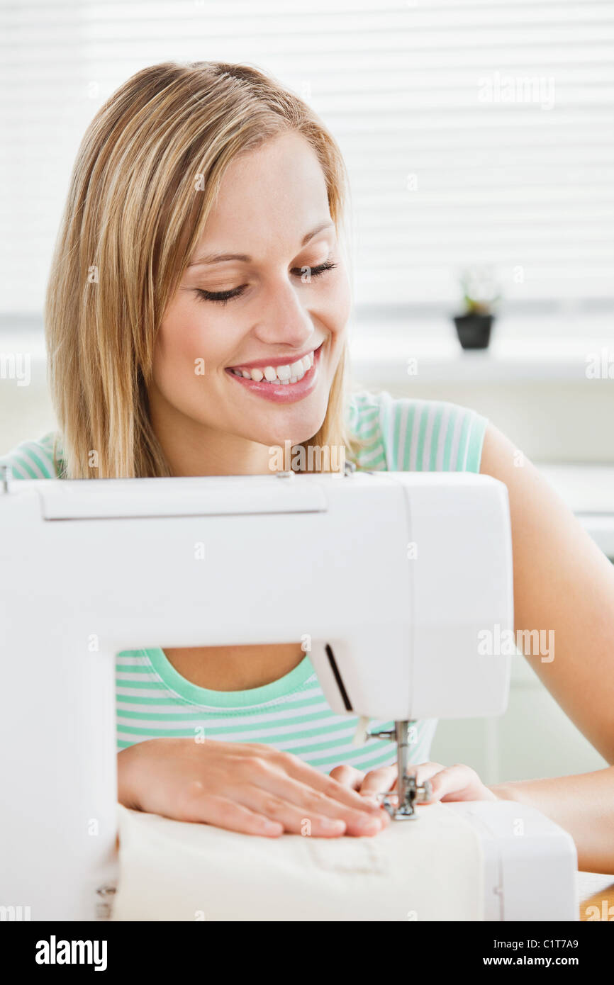 Ritratto di una donna sorridente cucire vestiti a casa Foto Stock