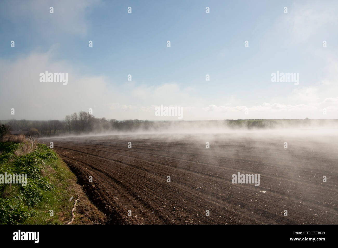 La nebbia che salgono dal campo la mattina presto luminoso caldo sole brucia fuori l'acqua dal campo arato Foto Stock