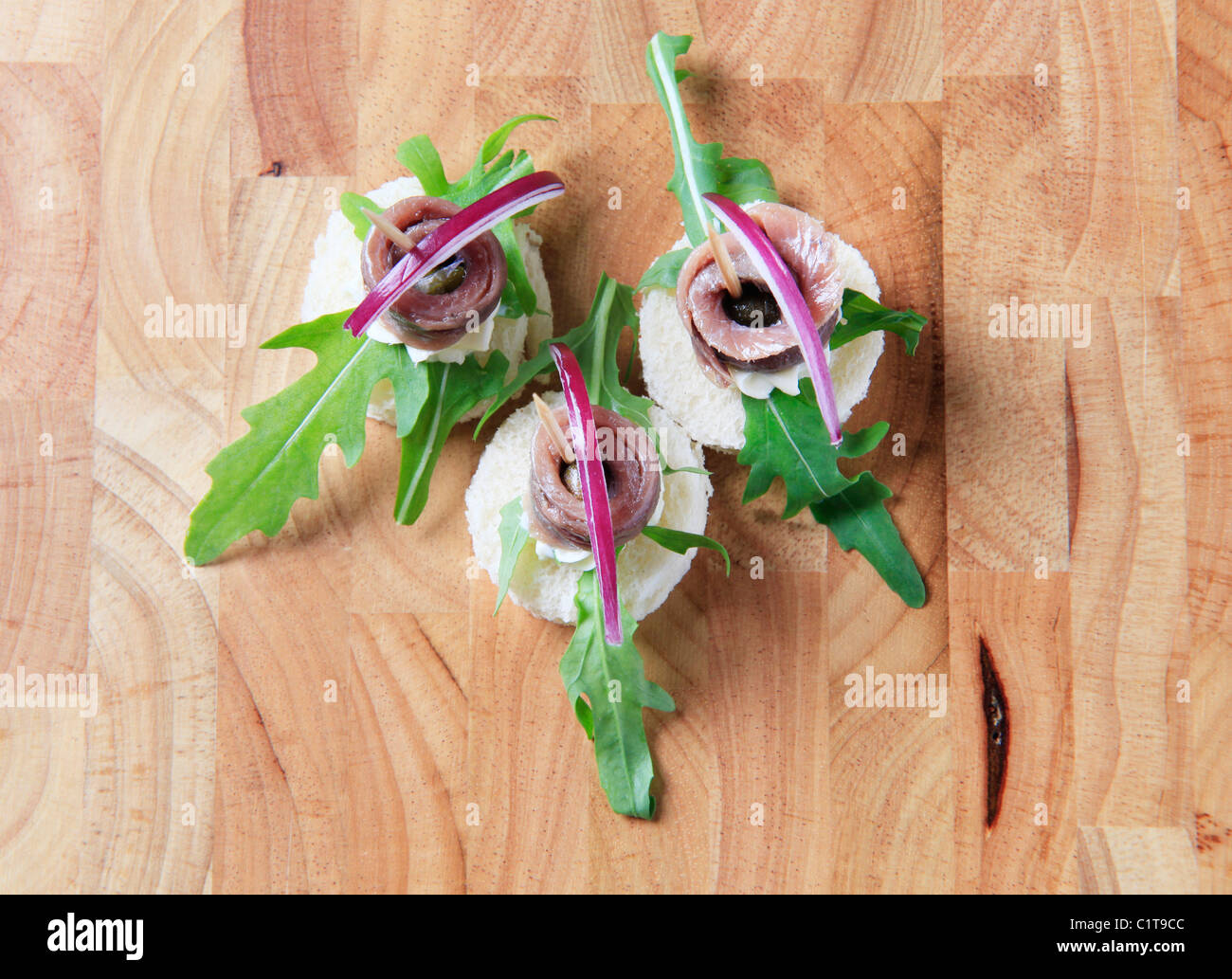 Crostini di acciuga guarnite con foglie di rucola e cipolla Foto Stock