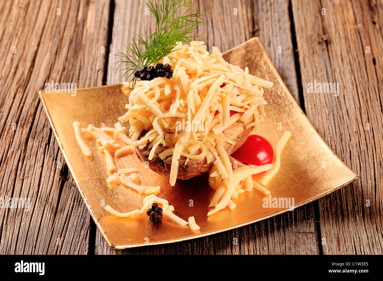 Patate al forno cosparso di formaggio Cheddar grattugiato Foto Stock