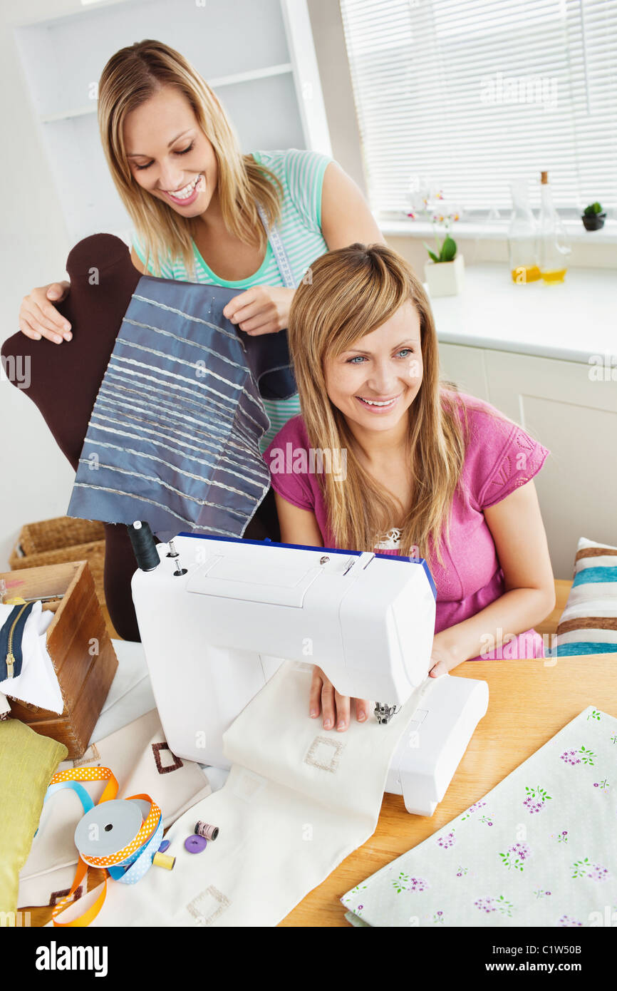 Felice giovani amici femminili abiti da cucire insieme a casa Foto Stock