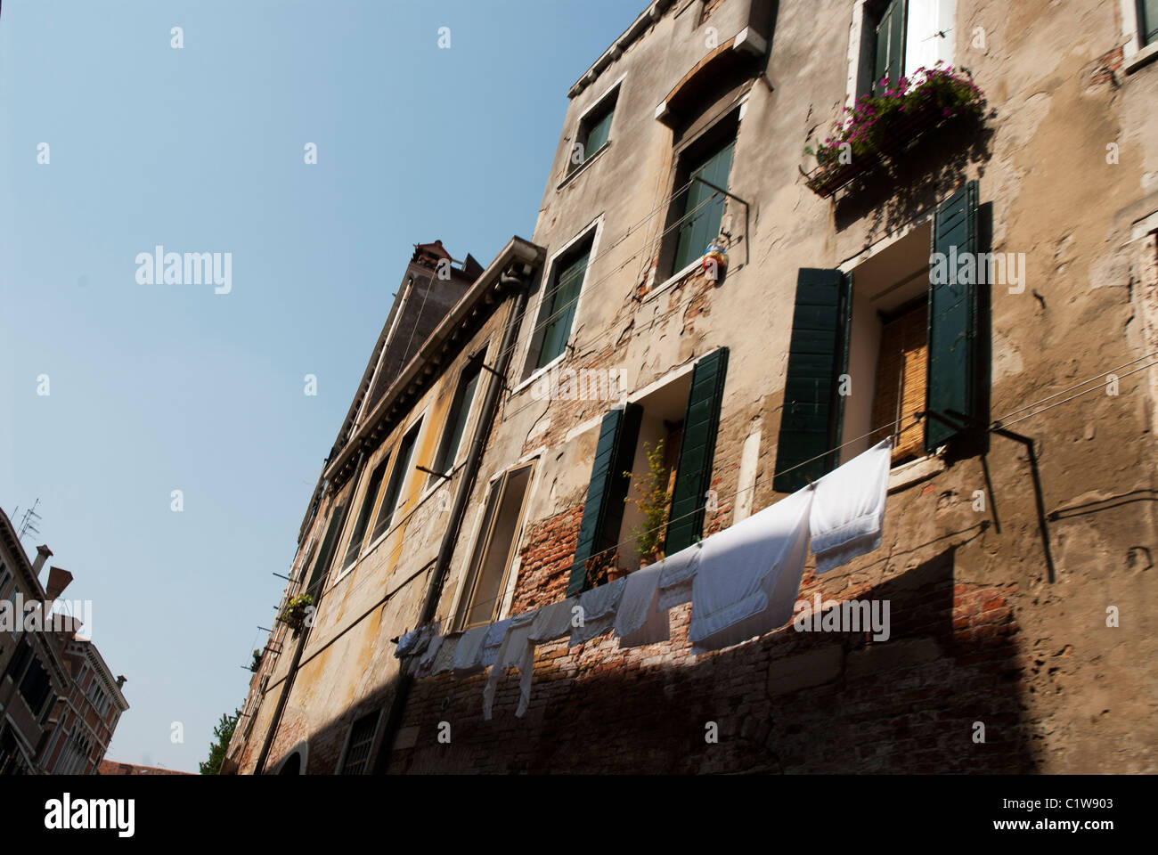 Punti di luce e ombre definire bianco fresco abbigliamento appeso fuori sulla linea di abbigliamento a Venezia, Italia. Foto Stock