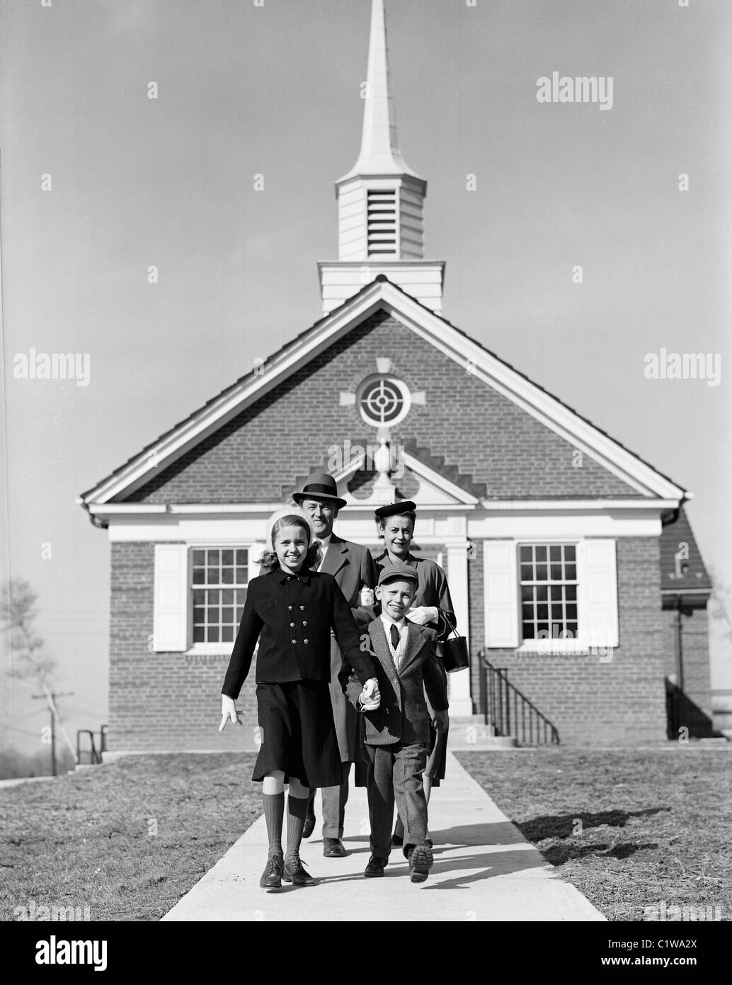 I genitori con bambini di fronte alla chiesa Foto Stock