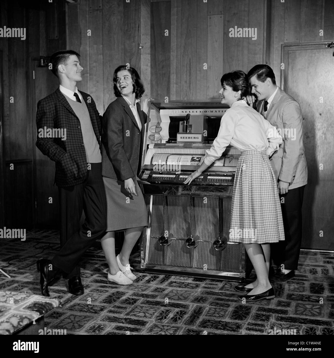 Due coppie giovani ascoltando musica dal jukebox Foto Stock