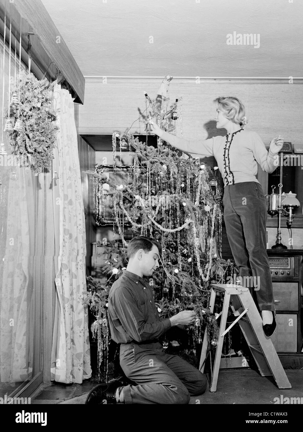 Giovane decorare albero di Natale a casa Foto Stock