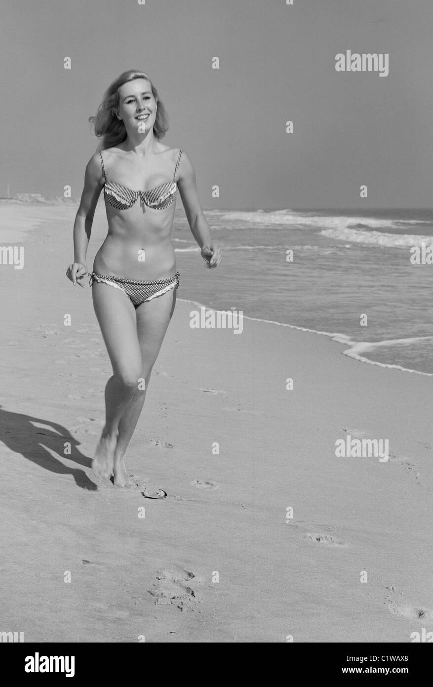 Giovane donna in bikini camminando sulla spiaggia Foto Stock
