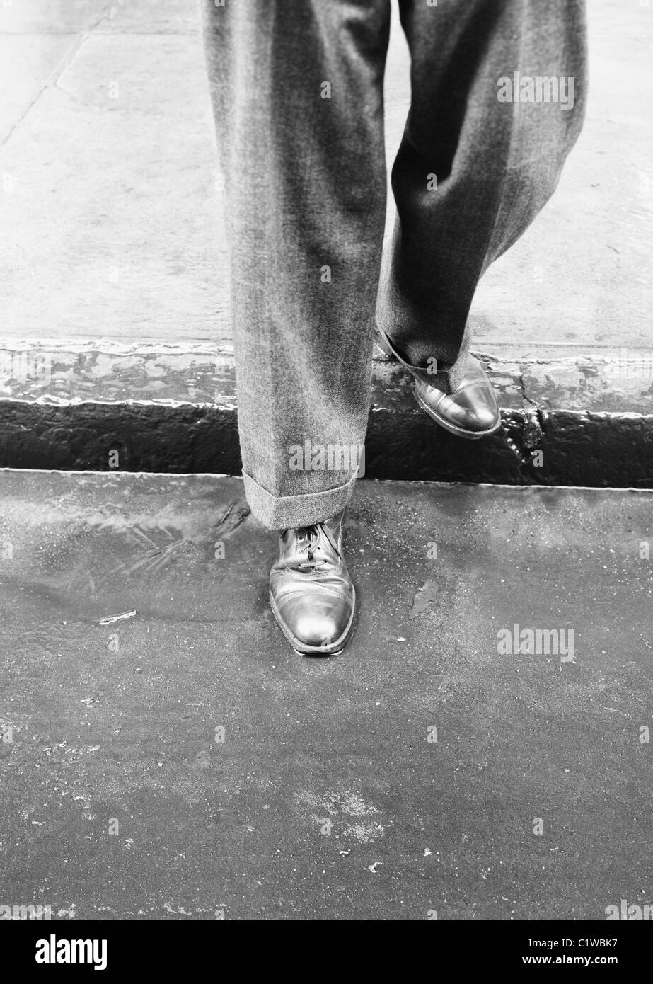 Uomo in piedi sul marciapiede sotto la pioggia, sezione bassa Foto Stock