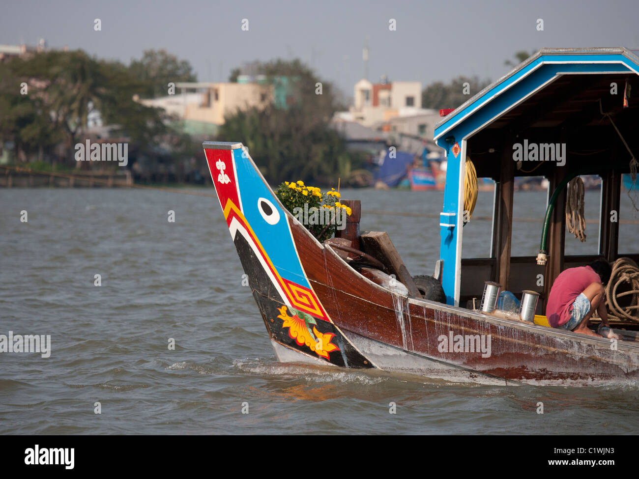 Uomo che pulisce il pesce sulla barca colorato prua del fiume Mekong Foto Stock