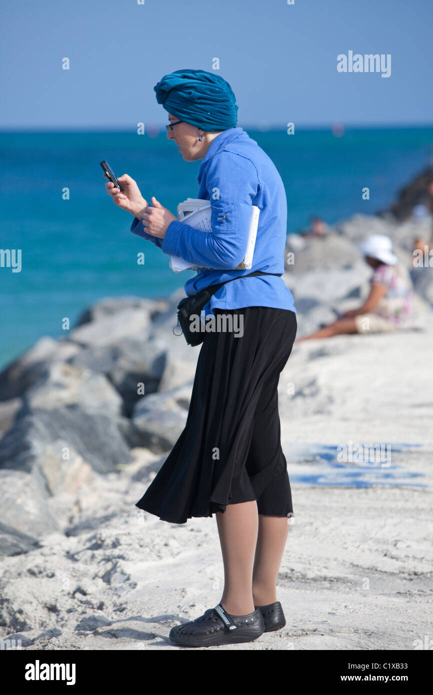 A piena lunghezza Ritratto di una donna per la messaggistica di testo sul suo telefono cellulare, Miami Beach, Stati Uniti d'America, America del Nord. Foto Stock