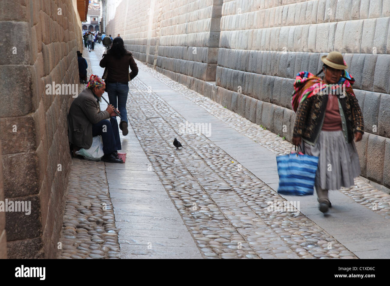 Una donna locale in abito tradizionale a piedi lungo una strada stretta a Cusco Foto Stock