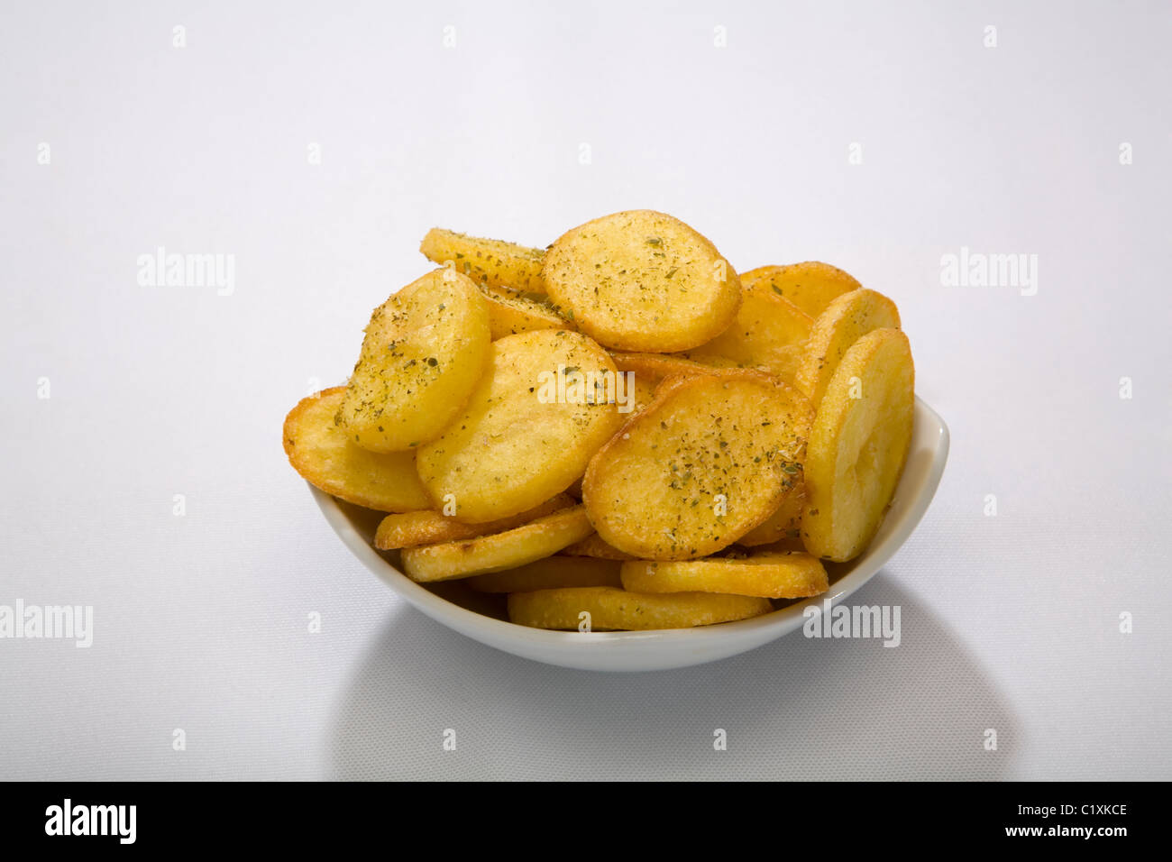 Patate fritte ciotola fette alimento giallo pepe sfondo bianco tovaglia mangiare stuzzicanti escort cucina commestibili olio grasso piastra fry Foto Stock