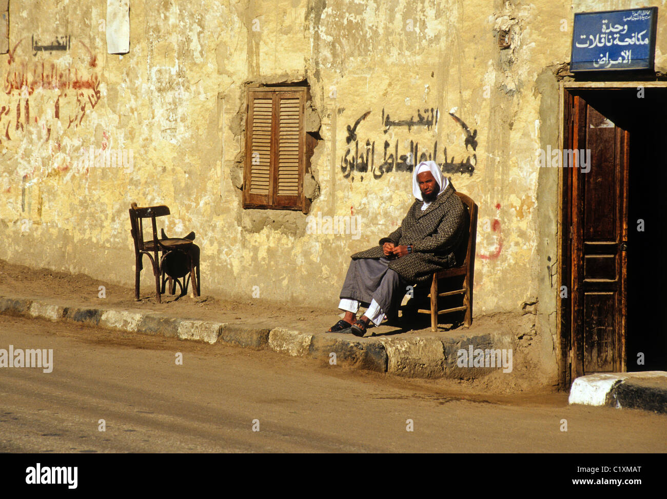 Uomo seduto in sun, Bawiti, Oasi Bahariya, Egitto Foto Stock