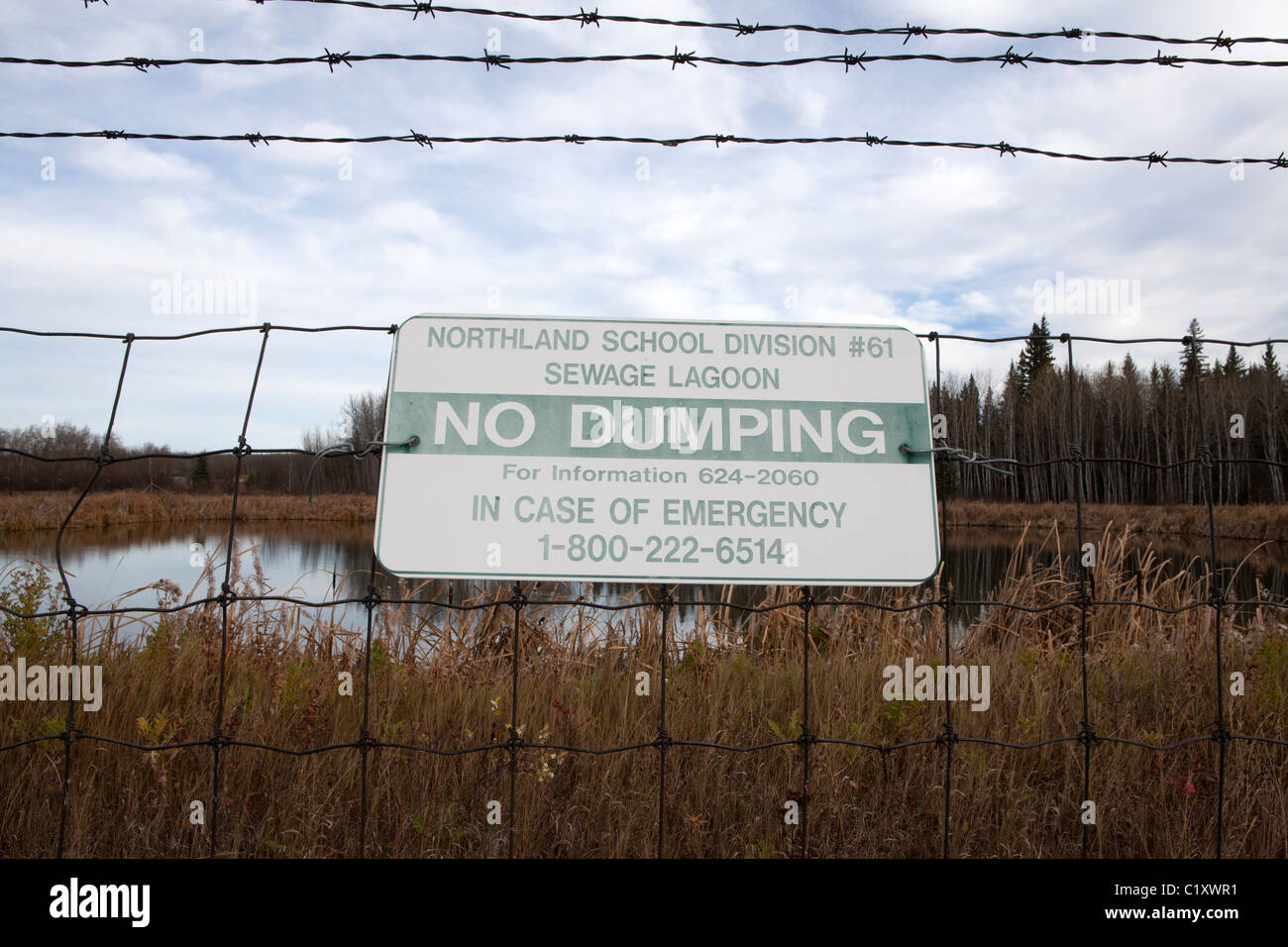 Segnale di avvertimento sul recinto di filo nella parte anteriore del liquame laguna, Peace River, Alberta, Canada Foto Stock