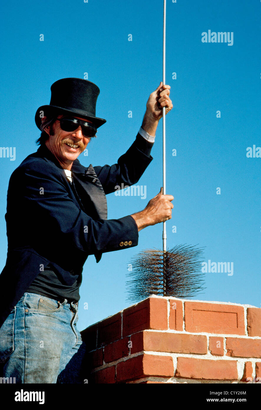Uno spazzacamino in black top hat e smoking rivestire--l'abbigliamento da  lavoro del suo commercio--si abbassa di una spazzola per iniziare la  pulizia di un camino di mattoni in California, Stati Uniti d'America