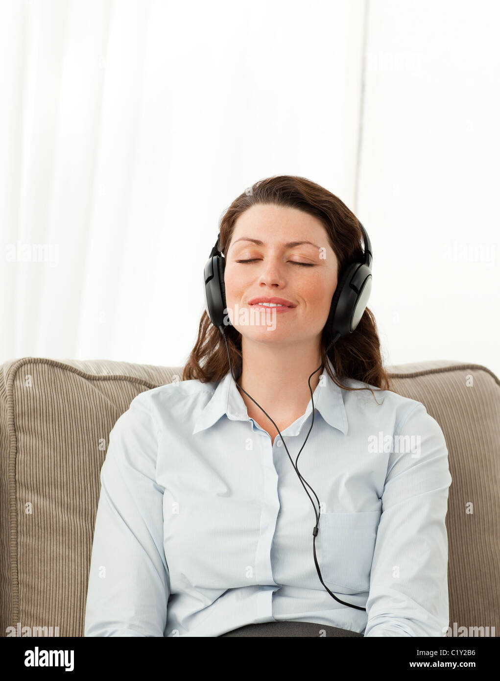 Donna rilassati ascoltando la musica con le cuffie nel soggiorno Foto Stock