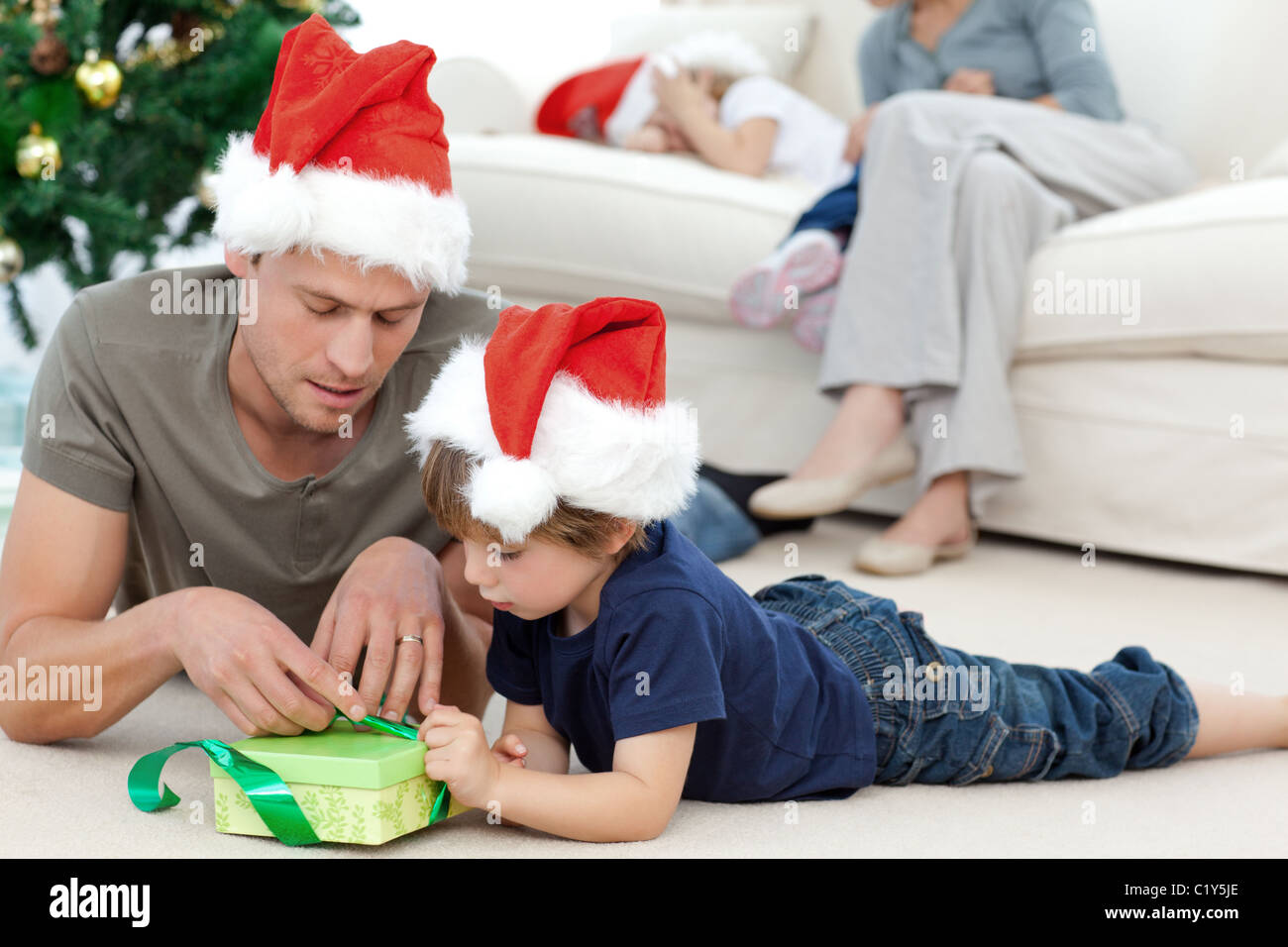 Padre e figlio scartare un presente sdraiato sul pavimento Foto Stock