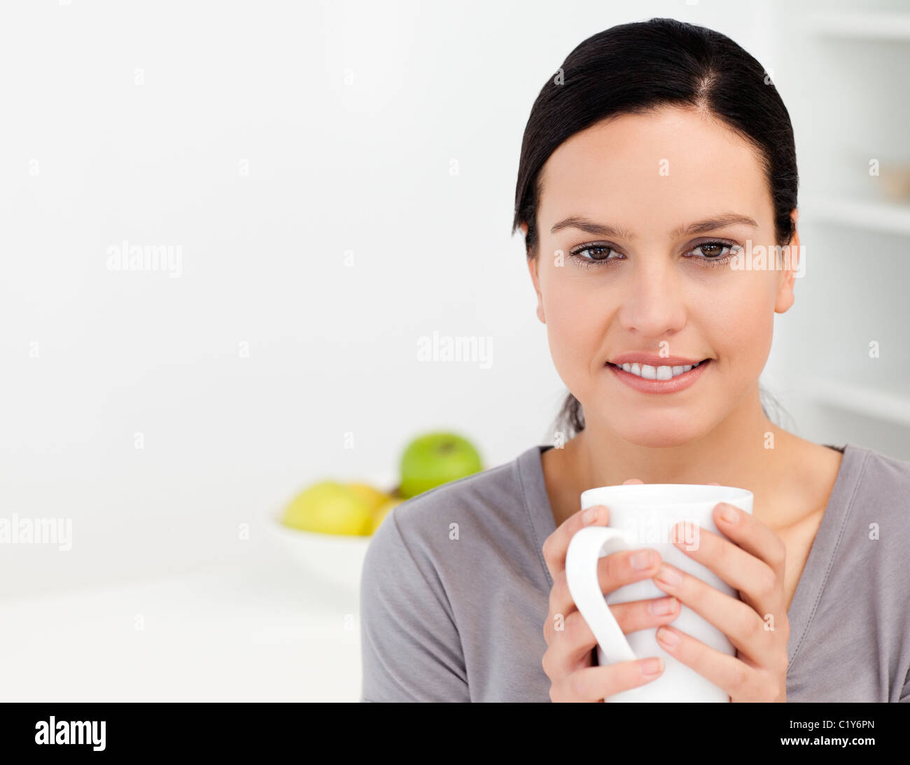 Bella donna tenendo una tazza di caffè mentre vi rilassate in cucina Foto Stock