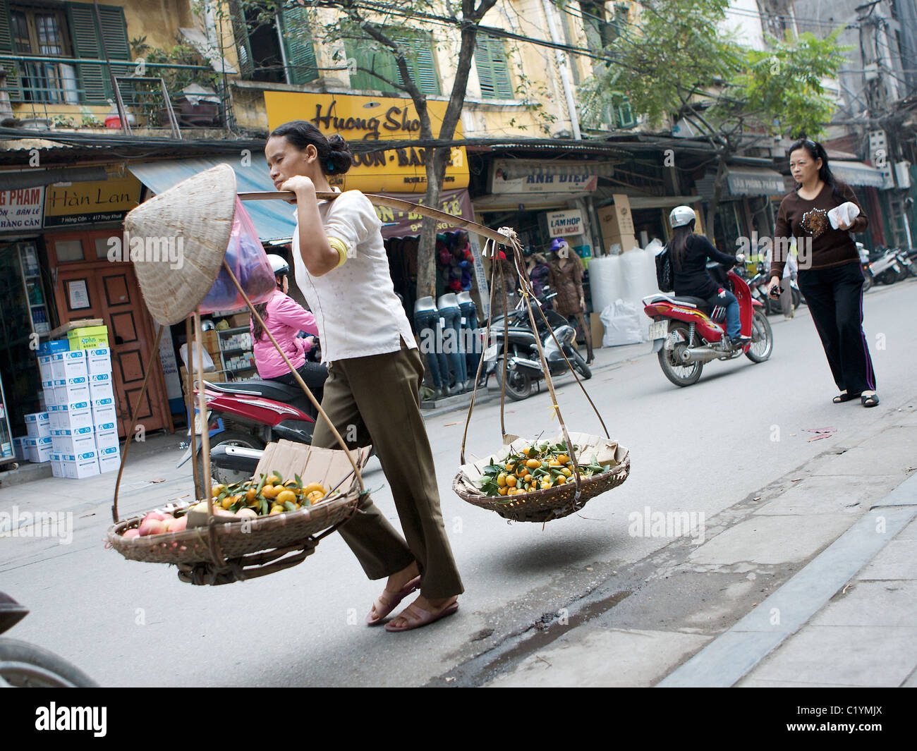 Ritratto di donna forcella portante sulle strade di Hanoi, Vietnam Foto Stock
