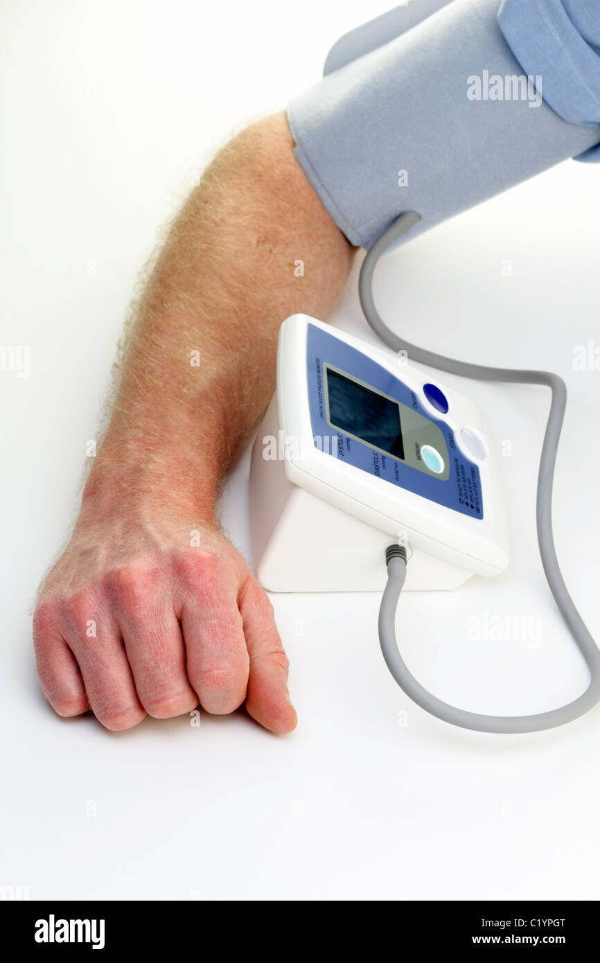 Mano e braccio del maschio visto misurando la sua pressione del sangue su un digitale del dispositivo di monitoraggio. Close-up di un mans braccio essendo misurata per la pressione sanguigna Foto Stock