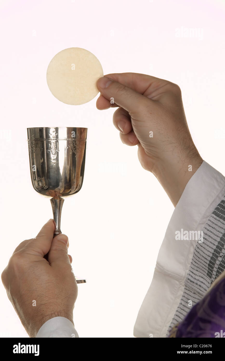 Un sacerdote cattolico durante la comunione nel culto Foto Stock