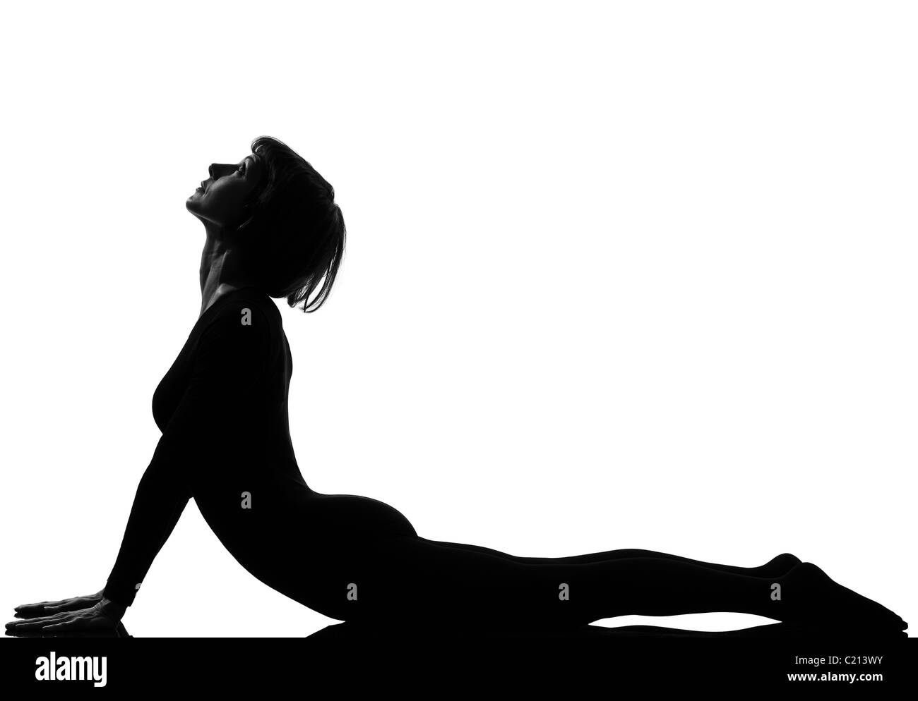 Donna sun salutation yoga surya namaskar postura cobra pongono in silouhette studio su sfondo bianco a piena lunghezza Foto Stock