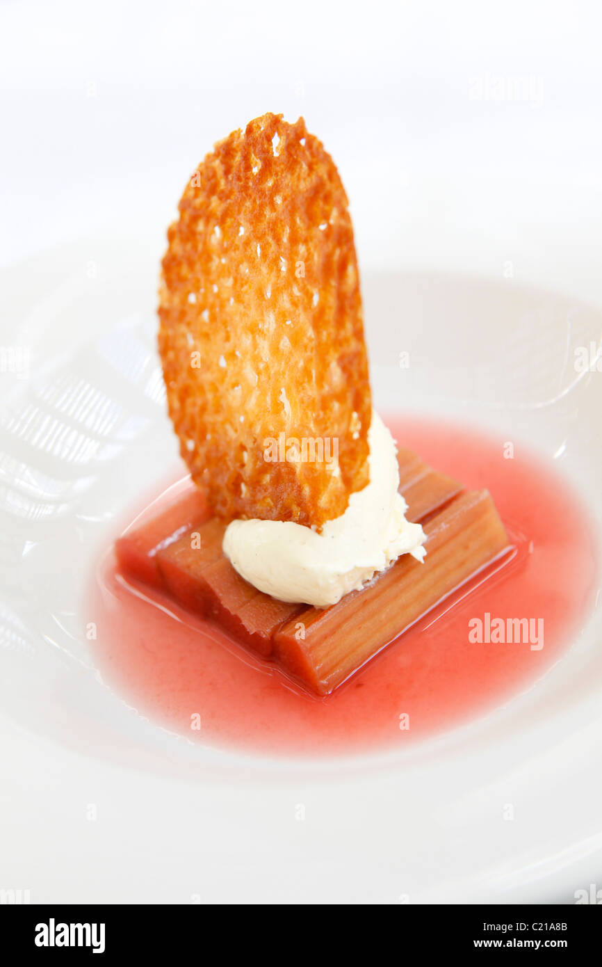 Dessert di rabarbaro speziato con panna e un brandy snap biscotto. Foto Stock
