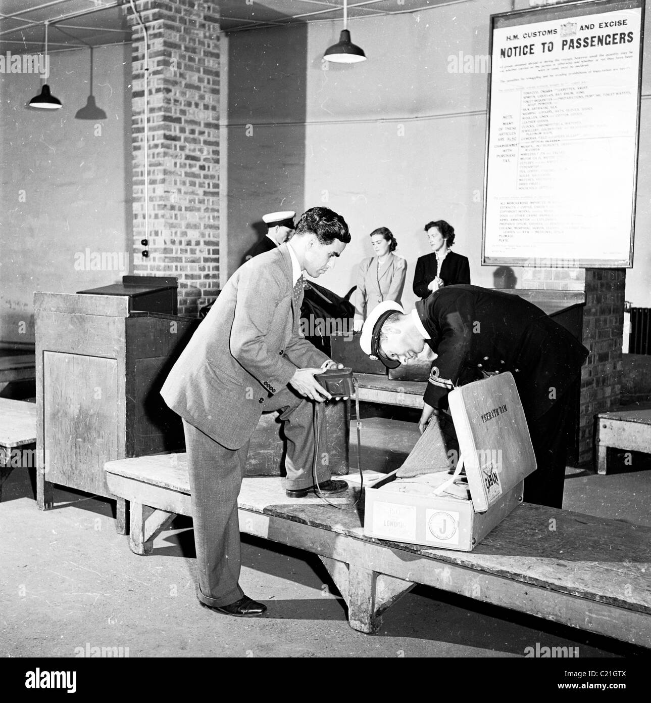 1950, storico, un visitatore d'oltremare appena arrivato in Gran Bretagna ha la sua valigia controllata da un ufficiale doganale in uniforme, Inghilterra, Regno Unito. Foto Stock