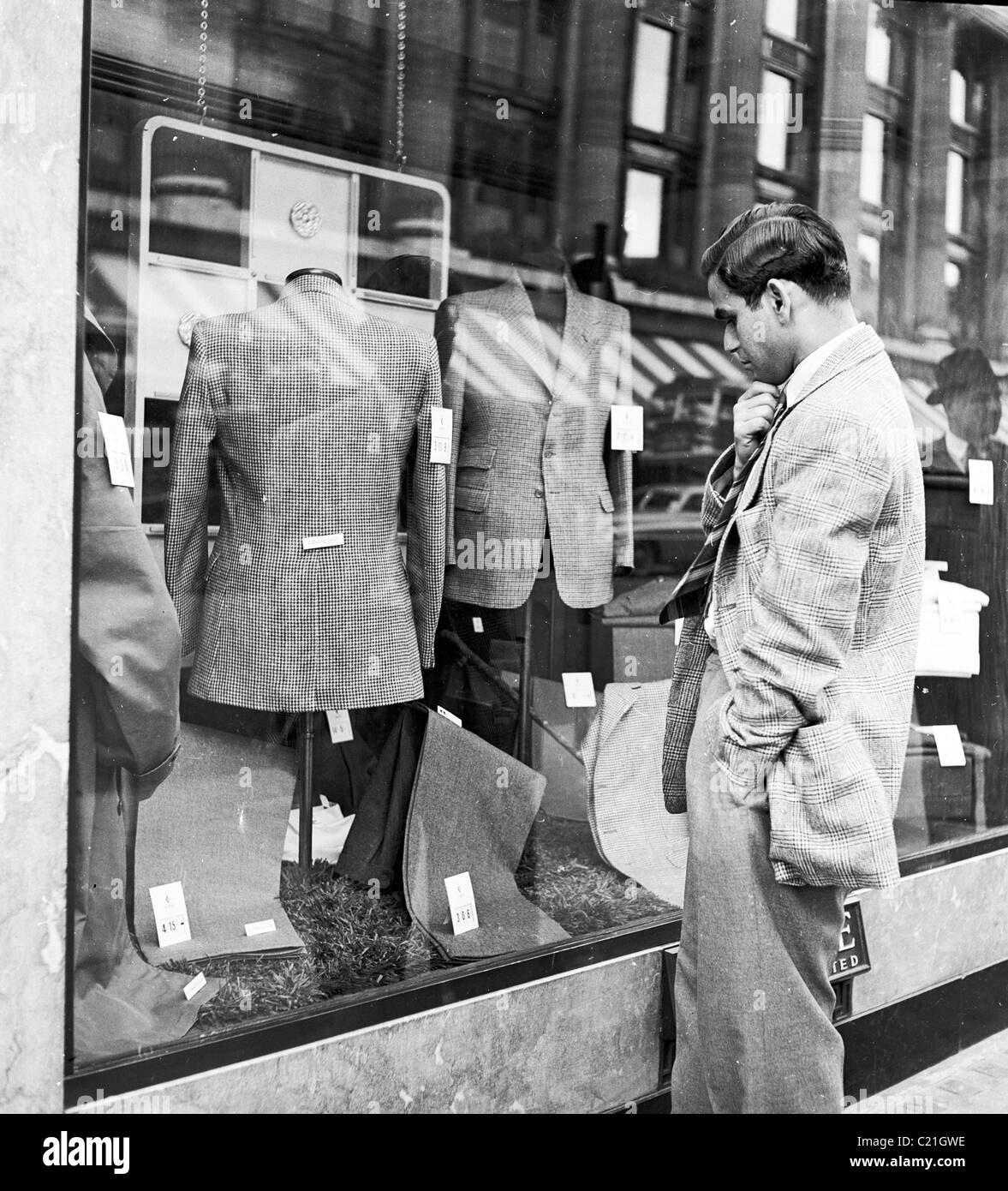 1950, un immigrato maschio appena arrivato nel Regno Unito che guarda una vetrina in un negozio di abbigliamento a Londra in questa foto storica di J Allan Cash. Foto Stock