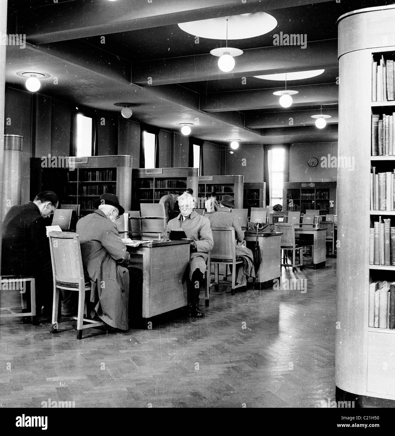 Degli anni Cinquanta, Inghilterra. Persone con lettura a tabelle in una biblioteca pubblica in questo quadro storico da J Allan contanti. Foto Stock