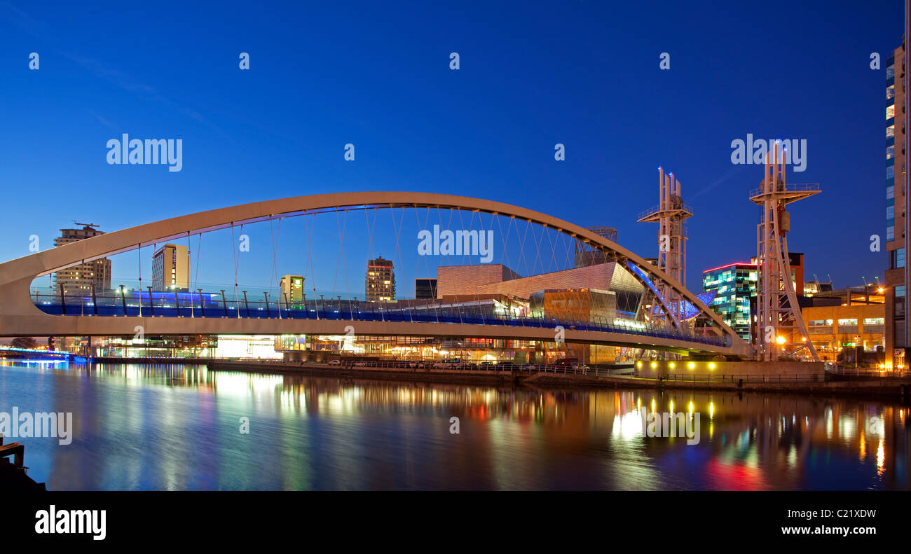 Inghilterra, Greater Manchester, Salford Quays, Lowry Centre e ponte illuminato al crepuscolo Foto Stock