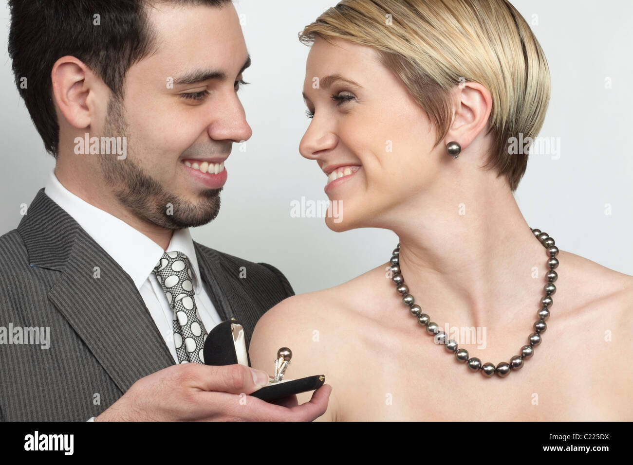 Bella donna che indossa gioielli di lusso:mentre l'uomo presenta un anello di esclusiva. La collana è un mare del sud collana di perle. Foto Stock