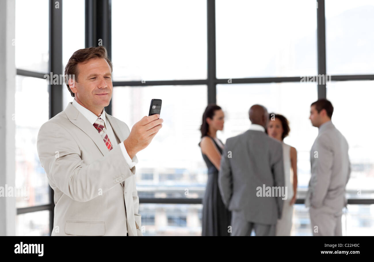Imprenditore tenendo un telefono al posto di lavoro con i colleghi Foto Stock