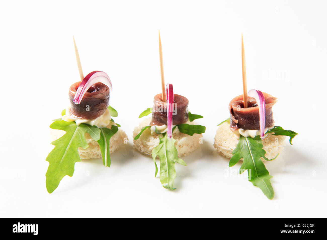 Crostini di acciuga guarnite con foglie di rucola e cipolla Foto Stock